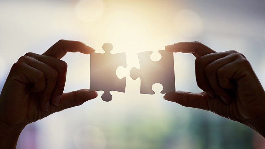 Hands bringing two puzzle pieces together